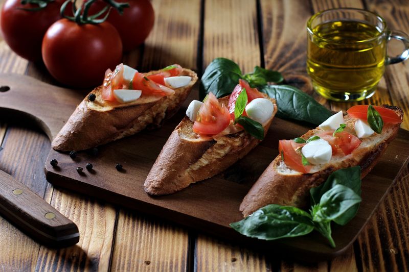 Assorted fresh toppings for marco pizza laid out on a wooden board